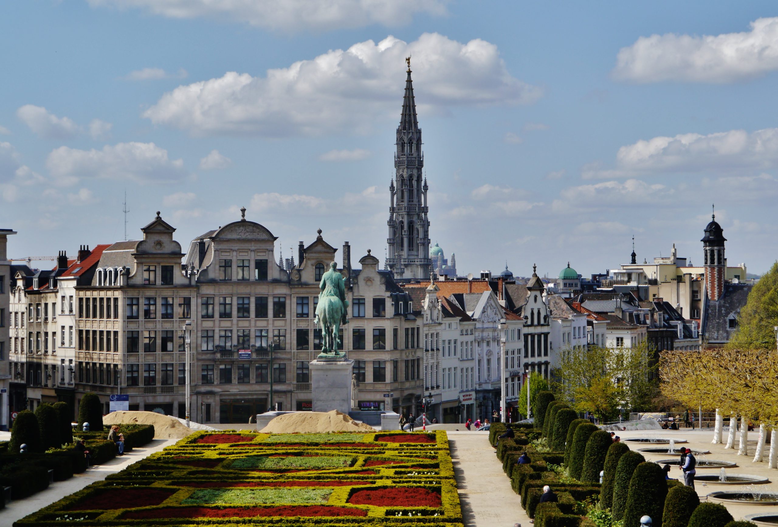 A picture of Mont Des Arts in Brussels. There are trees and shrubs in the picture and a statue. 